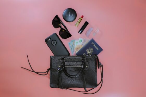Bolso Shopper- bolso negro con teléfono, lentes y maquillaje en fondo rosa